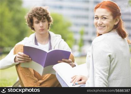 Portrait of happy young woman with male friend studying at college campus