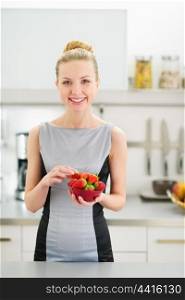 Portrait of happy young woman with plate of strawberries in modern kitchen