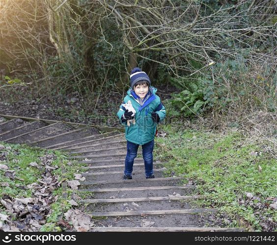 Portrait of healthy boy standing on step looking at camera with smiling face, Child explorer and learning about wild nature in countryside, Kid carrying backpack adventure in forest with school trip