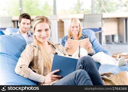Portrait of high school female student hold book - classmates in backround