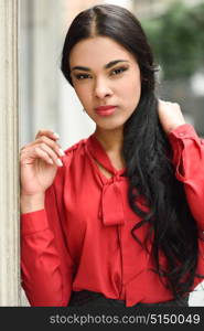 Portrait of hispanic bussinesswoman in urban background wearing red shirt and skirt