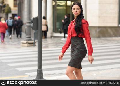 Portrait of hispanic bussinesswoman in urban background wearing red shirt and skirt