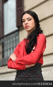 Portrait of hispanic bussinesswoman in urban background wearing red shirt and skirt