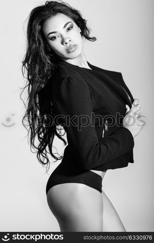 Portrait of hispanic woman wearing black jacket and panties on white background. Studio shot