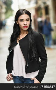 Portrait of hispanic young woman wearing casual clothes in urban background