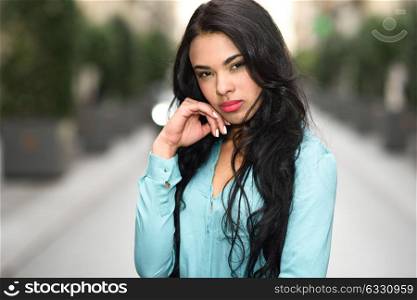 Portrait of hispanic young woman wearing casual clothes in urban background