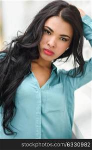 Portrait of hispanic young woman wearing casual clothes in urban background