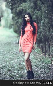 Portrait of hispanic young woman wearing orange dress in urban park