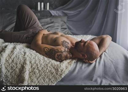 Portrait of hunky men resting on the bed.. Man with naked torso lies on the bed 19.