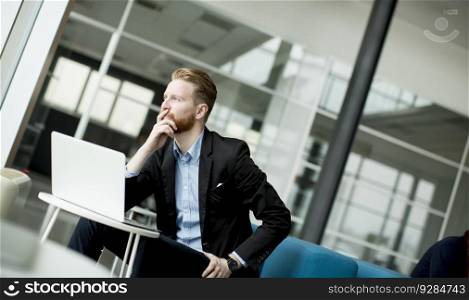 Portrait of imagined redhead young businessman working  on laptop or notebook
