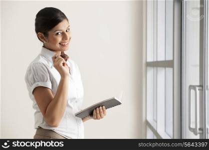 Portrait of Indian businesswoman smiling while holding diary