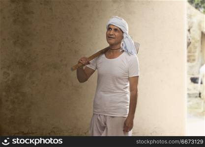 Portrait of Indian old farmer carrying hoe on his shoulder