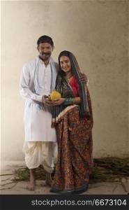 Portrait of Indian rural couple holding clay piggy bank