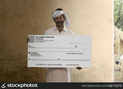 Portrait of Indian rural farmer showing a bank cheque