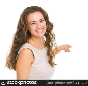 Portrait of interested young woman pointing back on copy space