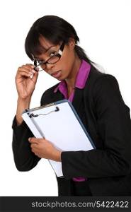 portrait of intimidating black businesswoman with glasses lowered holding clipboard