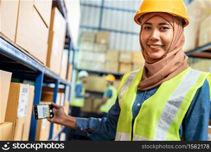 Portrait of Islam Muslim female warehouse worker use mobile phone scan qr code for online inventory in warehouse distribution environment. Using in business warehouse technology and logistic concept.