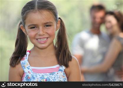 portrait of jovial little girl with parents in background