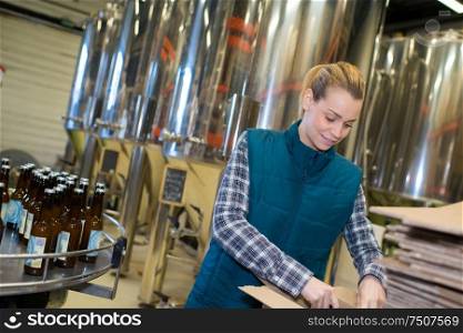 portrait of joyful young female technologist on beer brewery factory