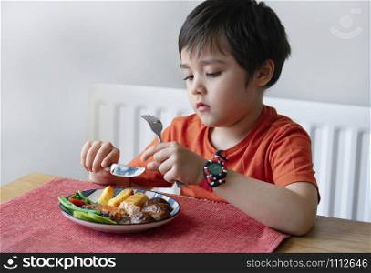 Portrait of kid with bored face having steak salmon and chips for Sunday dinner at home, Unhappy child eating lunch, Children eating heathy and Fresh food. Spoiled child concept