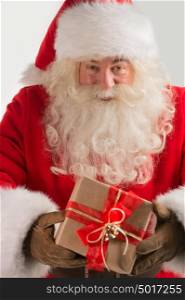 Portrait of kind Santa Claus with christmas present and looking at camera