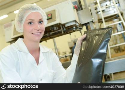 Portrait of lady in factory holding sealed black bag