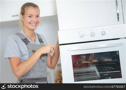 Portrait of lady repairing oven