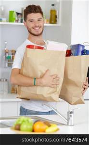 portrait of latin young man holding grocery shopping bags