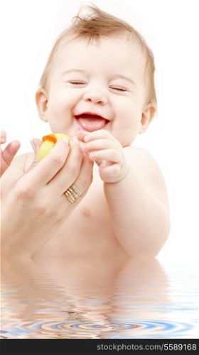 portrait of laughing baby boy in water playing with rubber duck