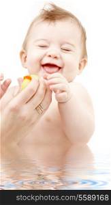 portrait of laughing baby boy in water playing with rubber duck
