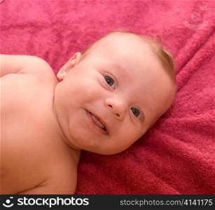 Portrait of laughing baby boy lying on the bed