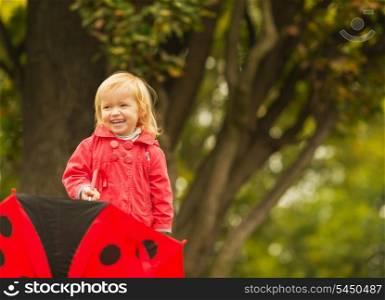 Portrait of laughing baby with red umbrella