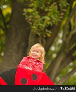 Portrait of laughing baby with red umbrella looking up