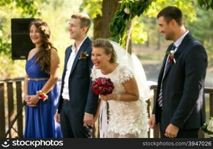 Portrait of laughing bride and groom posing at outdoor wedding ceremony