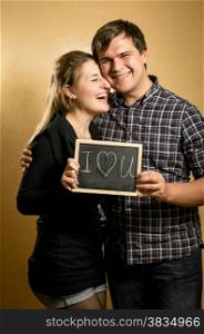Portrait of laughing couple in love holding blackboard with written word
