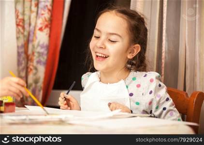 Portrait of laughing girl drawing on canvas