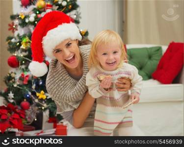 Portrait of laughing mother and eat smeared baby near Christmas tree