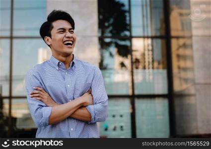 Portrait of Laughing Young Asian Businessman in the City. Crossed Arms and looking away. a Happy Friendly Man