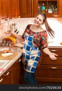 Portrait of laughing young housewife in apron on kitchen