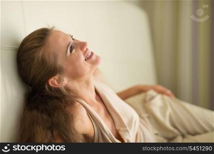 Portrait of laughing young woman laying on couch