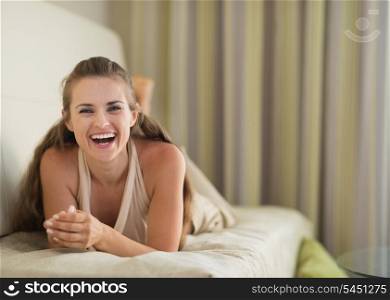 Portrait of laughing young woman laying on divan