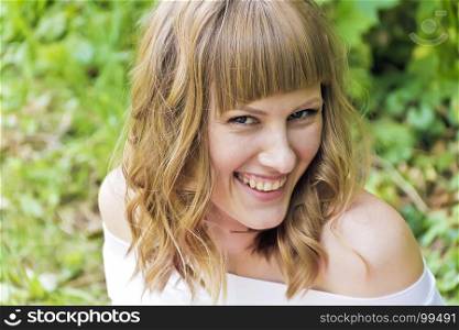 Portrait of laughing young woman with blond hair in sunlight