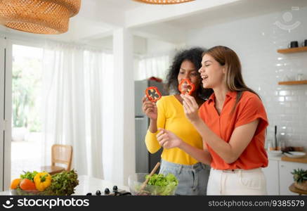 Portrait of LGBT Couple young women eating salad and smiling while standing in kitchen at home