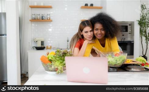 Portrait of LGBT Couple young women eating salad and smiling while standing in kitchen at home