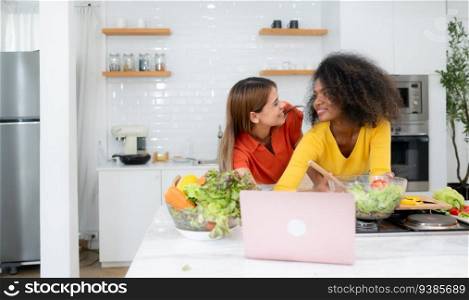 Portrait of LGBT Couple young women eating salad and smiling while standing in kitchen at home