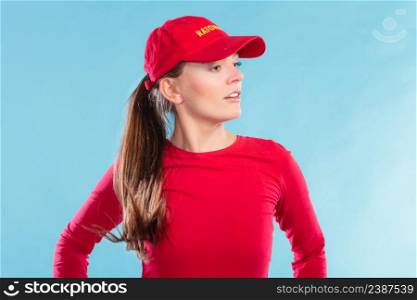 Portrait of lifeguard woman girl in red cap with ratownik sign on blue. Accident prevention rescue.. Portrait of lifeguard woman in red cap.