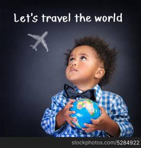 Portrait of little African schoolboy holding in hands small globe, dreaming about traveling all over the world, happy childhood concept