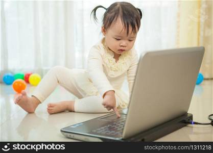 Portrait of little asian girl play laptop in home