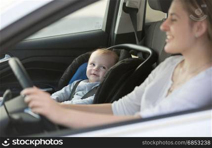 Portrait of little baby boy sitting in car at safety seat