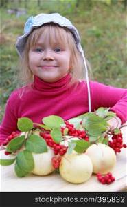 Portrait of little baby with apples and schisandra. Joyful baby smiling near crop of fruits. Portrait of little baby with apples and schisandra